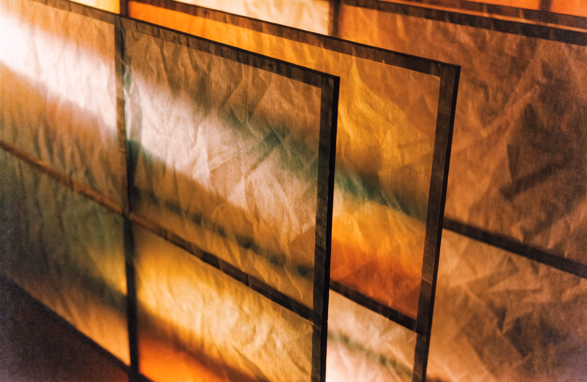 Warm light glowing through translucent layered paper screens, soft folds and gentle shadow.